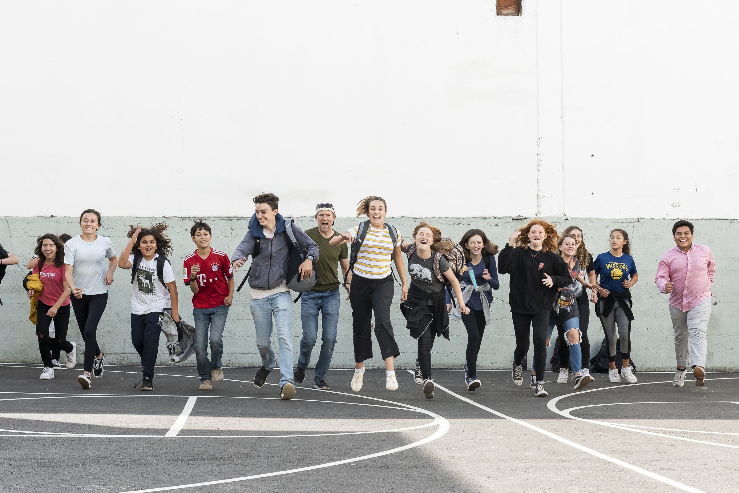 Students running together across the play court toward the camera