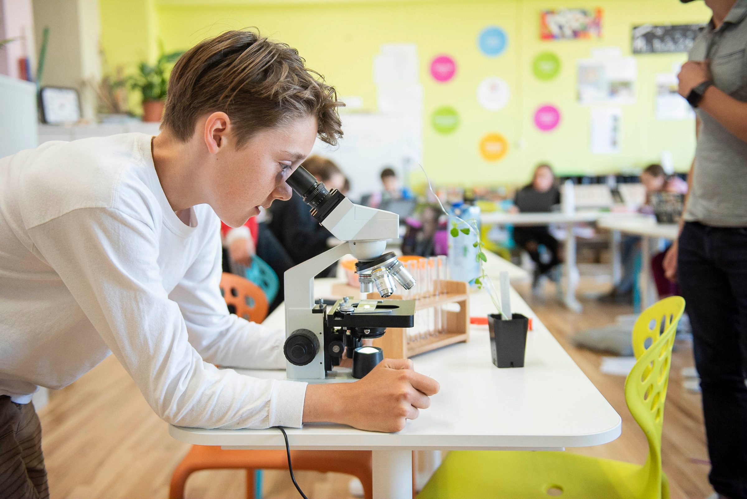 Middle school student looking into a microscope in a science classroom