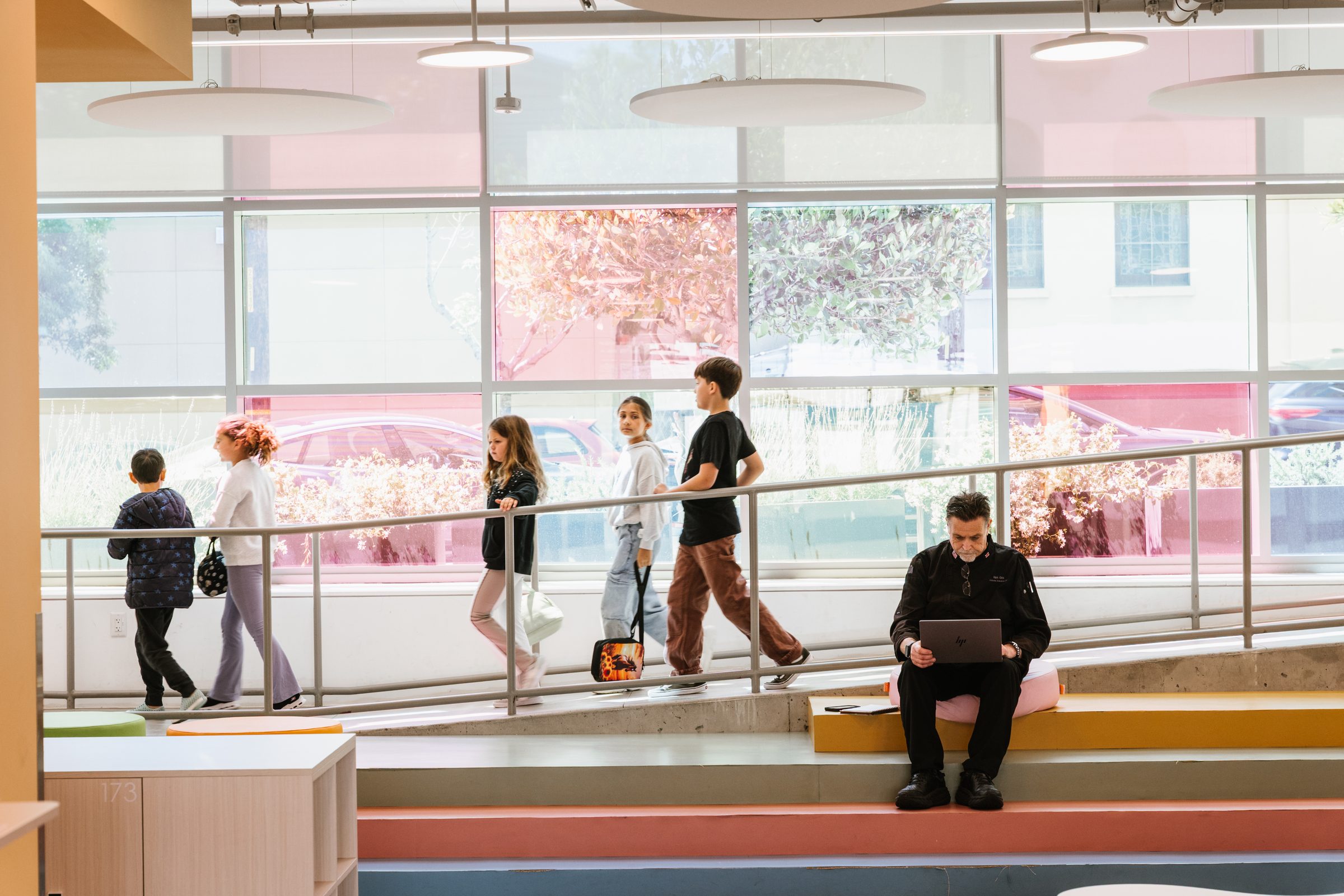 Students crossing the interior walkway above the atrium at the Mission campus