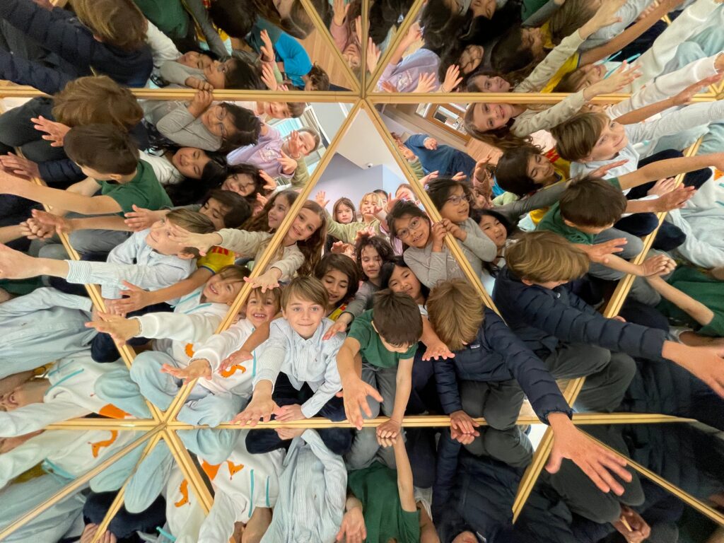 Students lying in a circle with their heads together, seen from above