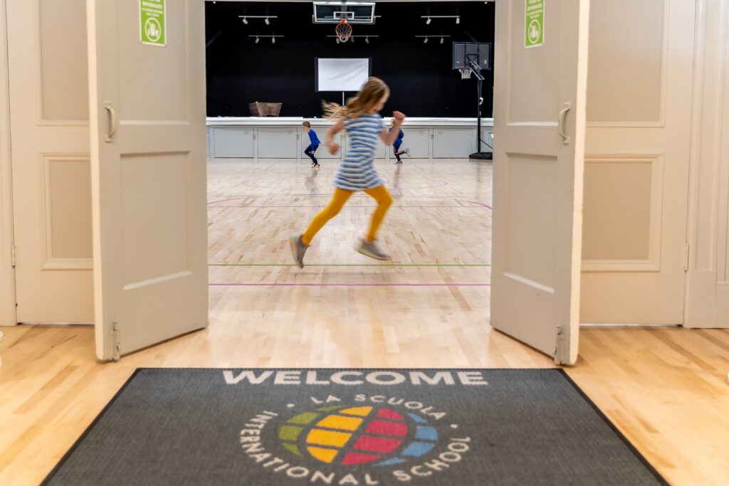 A child running through the doors onto the school's welcome mat
