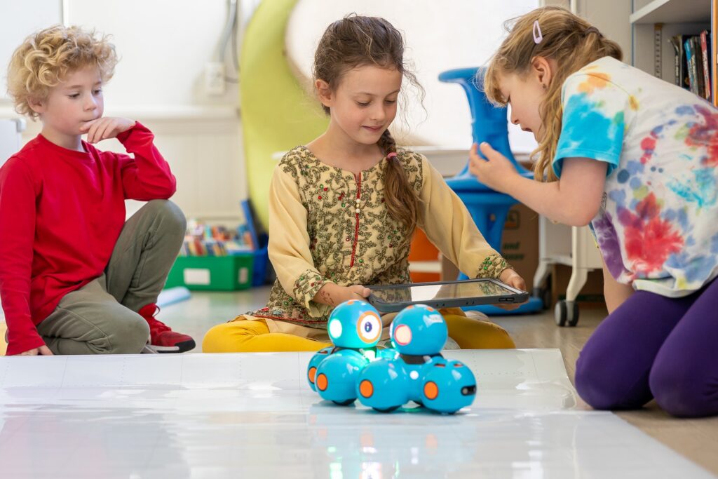 Younger students programming a robot on the classroom floor