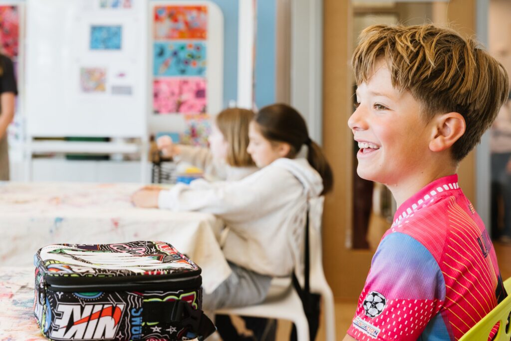 A student smiling in class with a project on the table
