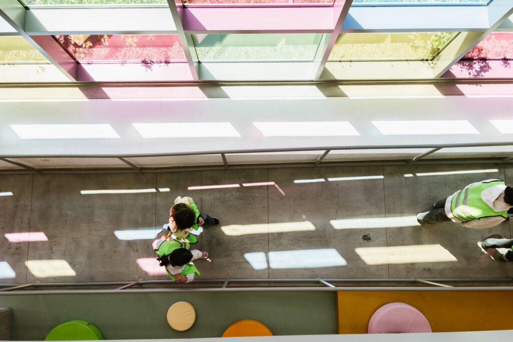 A child crossing the sunlit atrium under the coloured skylights