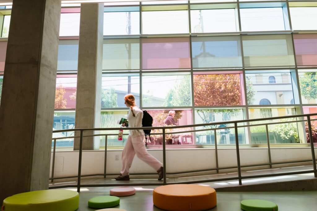 A student walking the upper walkway past the coloured windows