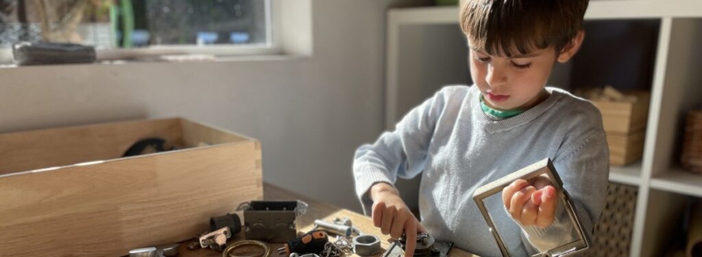 Child taking apart salvaged machine parts at a wooden table