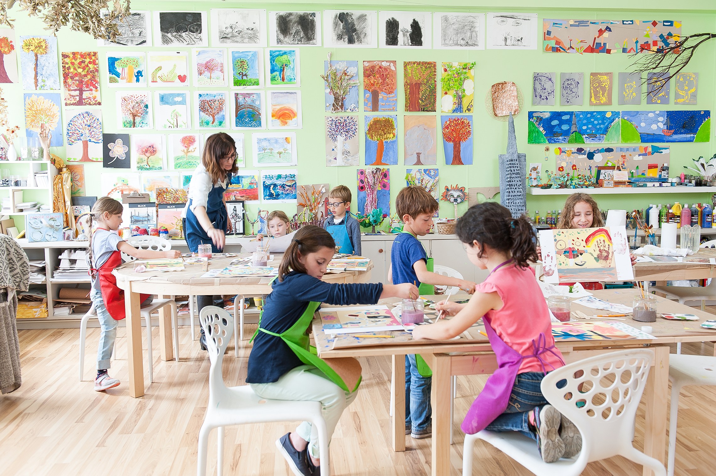 Children working at tables in an atelier lined with student artwork