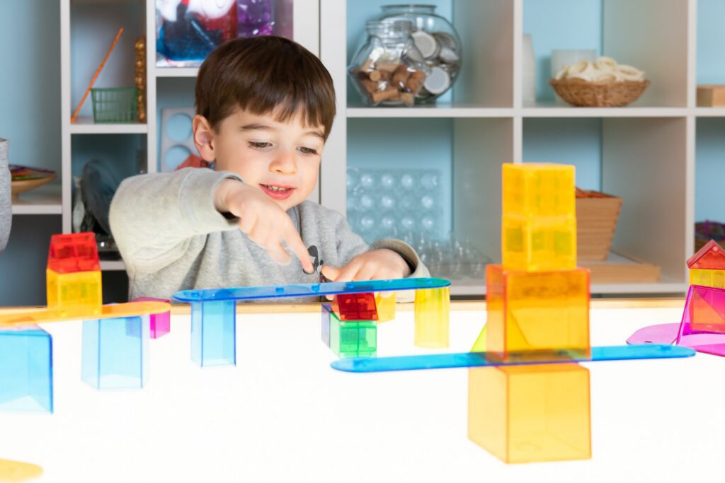 A preschooler balancing translucent coloured blocks