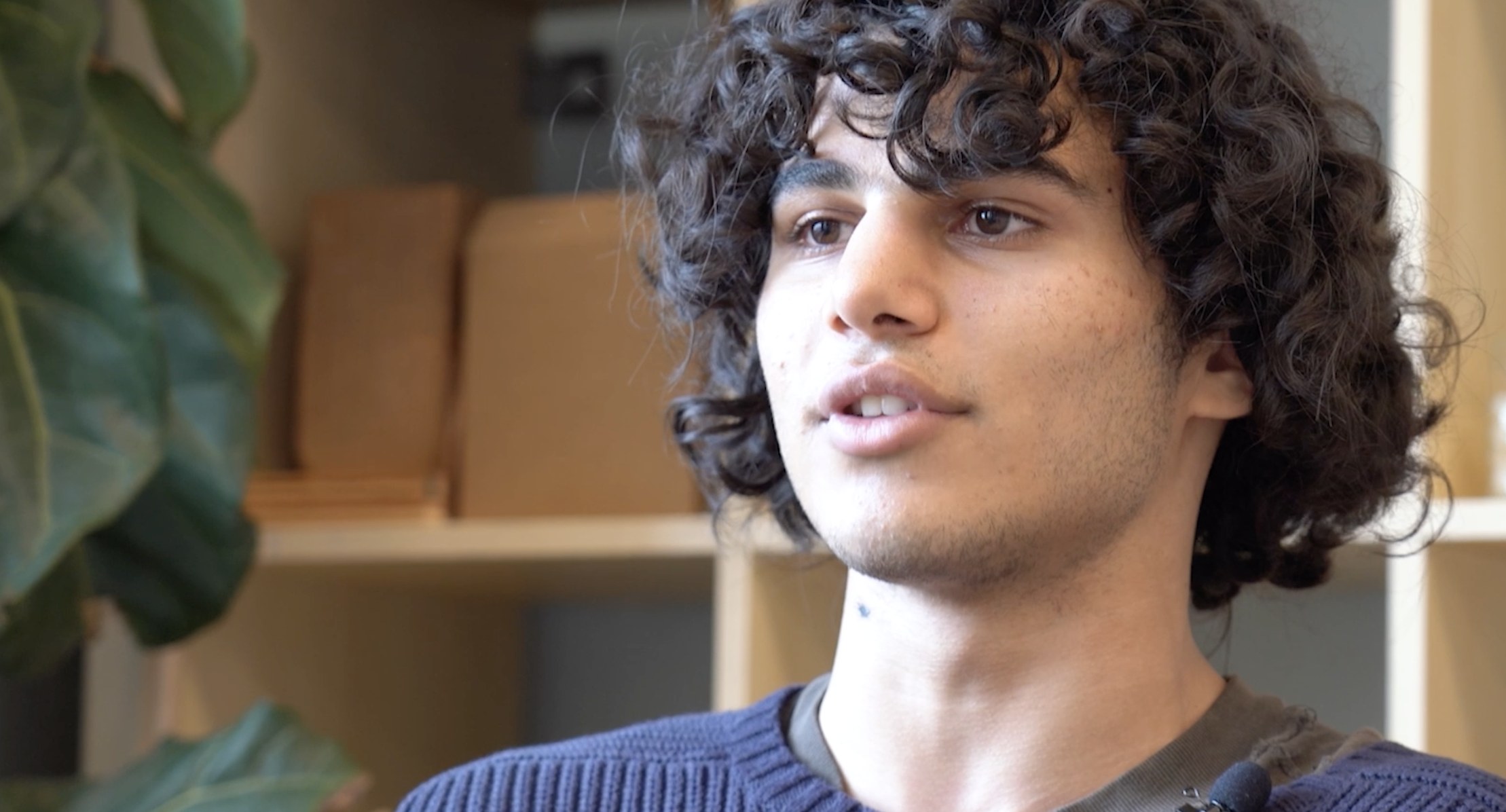 A La Scuola alumnus speaking on camera in front of a bookshelf