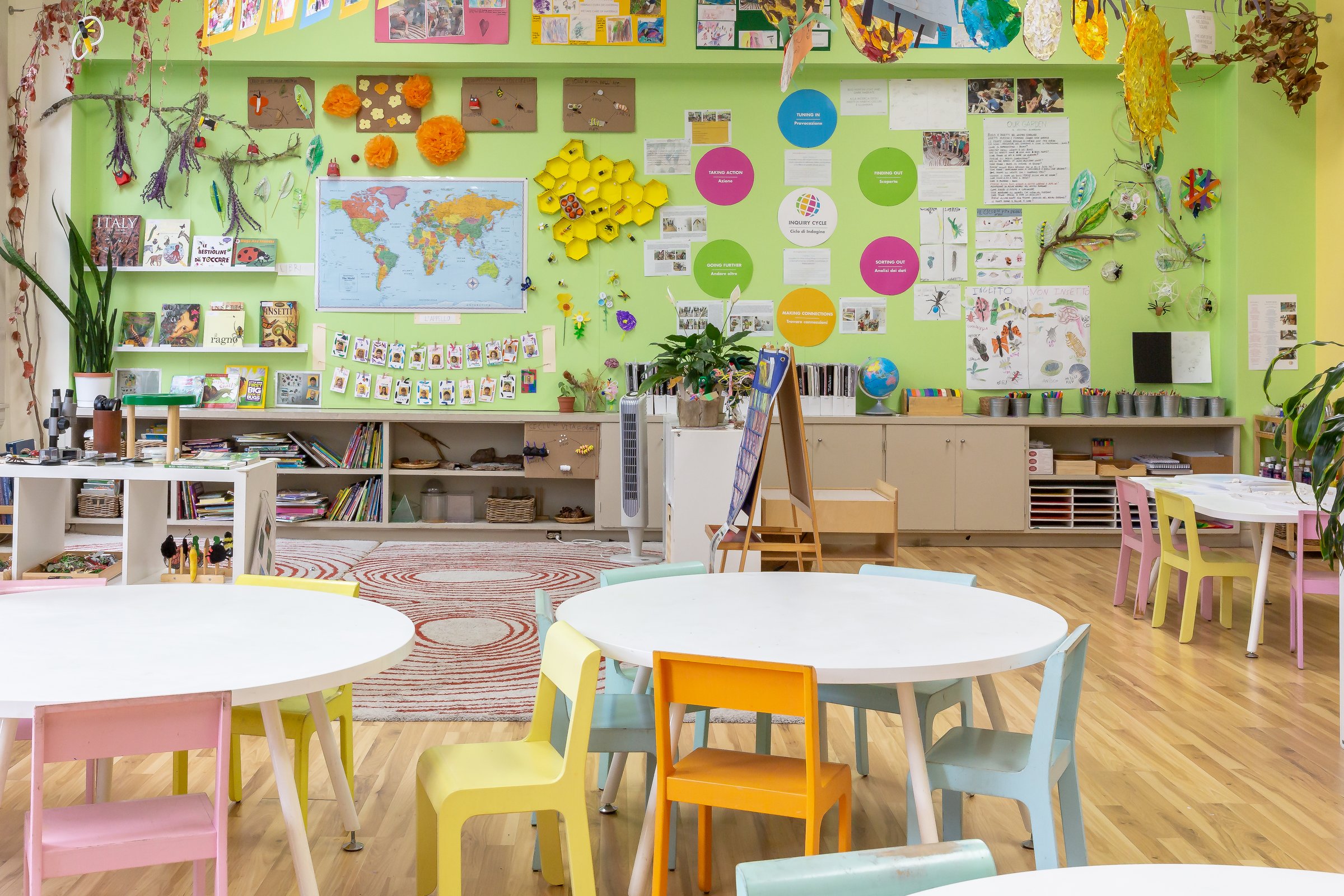 A bright preschool classroom with round tables, small colourful chairs and a lime-green wall